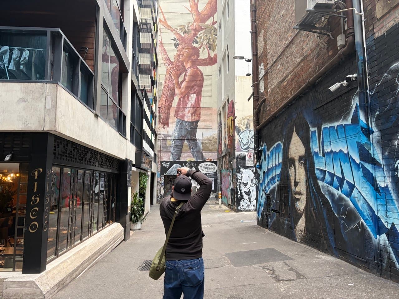 A student photographing street art in a Melbourne CBD laneway during a photography course